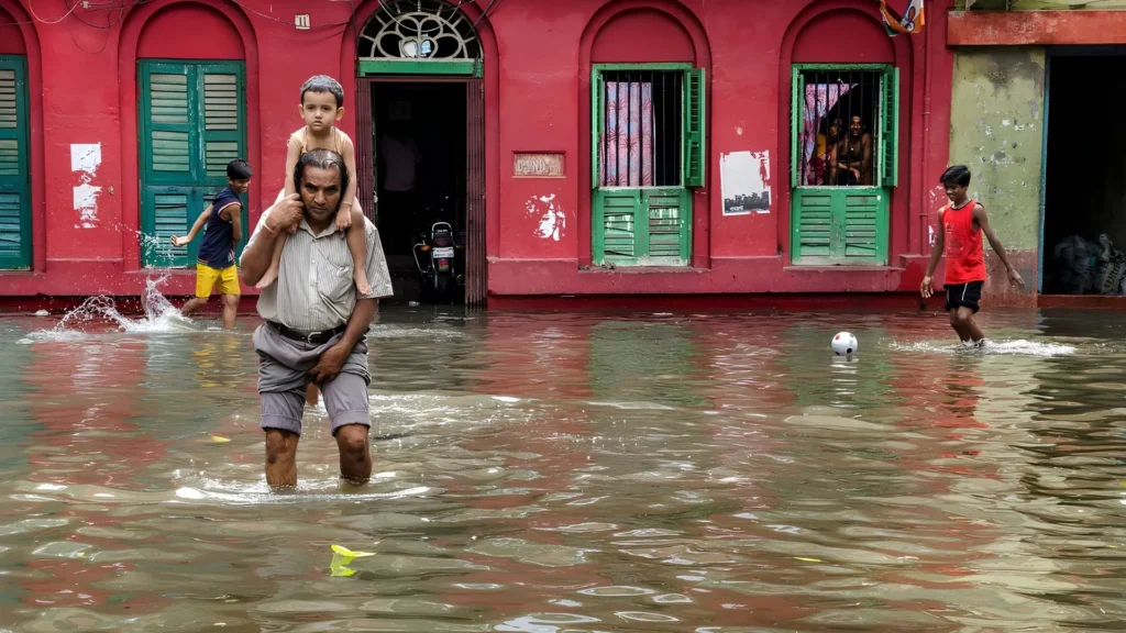 Grandfather carrying child through flooded street