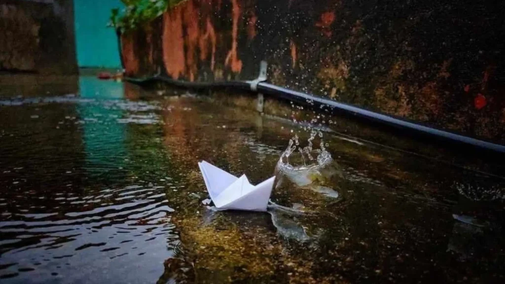 Paper boat floating in a rain puddle